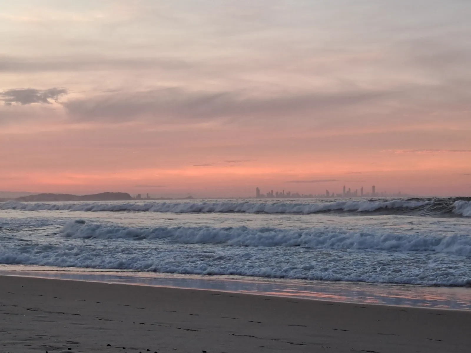 A wide orange sky over the beach, skyline on the horizon