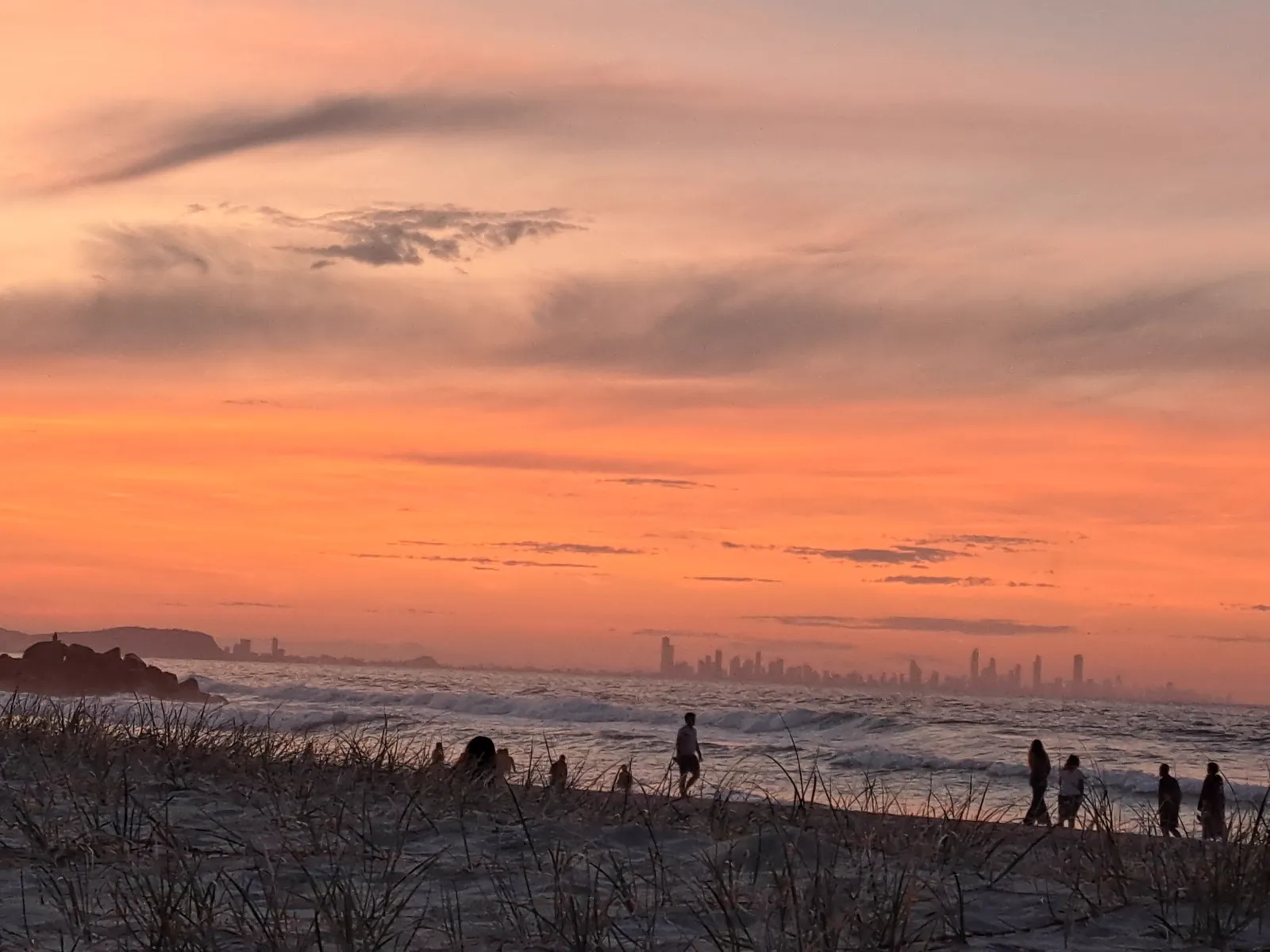Dusk strollers silhouetted at the water's edge